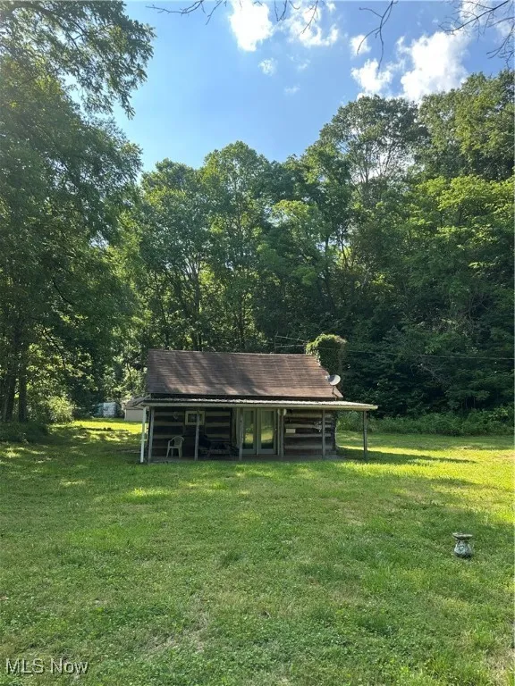 View of green lawn featuring a wooded view