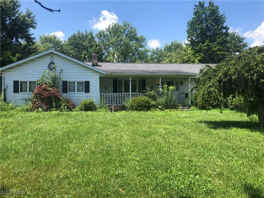 View of front of property with a porch, a front lawn, and a chimney