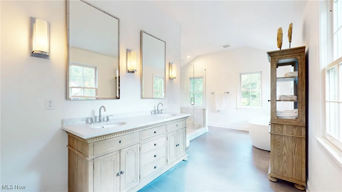 Full bath with plenty of natural light, dobule double vanity, a freestanding tub, a shower stall, and lofted ceiling