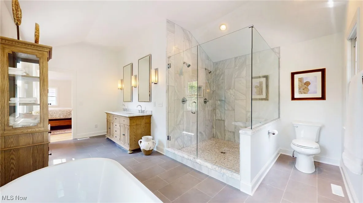 Bathroom featuring lofted ceiling, a soaking tub, extra large Cararra marble tile stall shower, double vanity, and tile patterned floors
