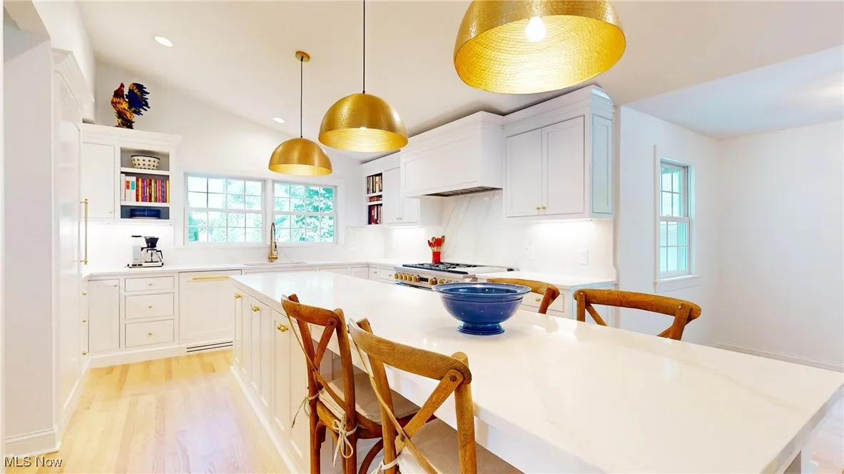 Kitchen featuring open shelves, paneled dishwasher, a breakfast bar center island, and white cabinets