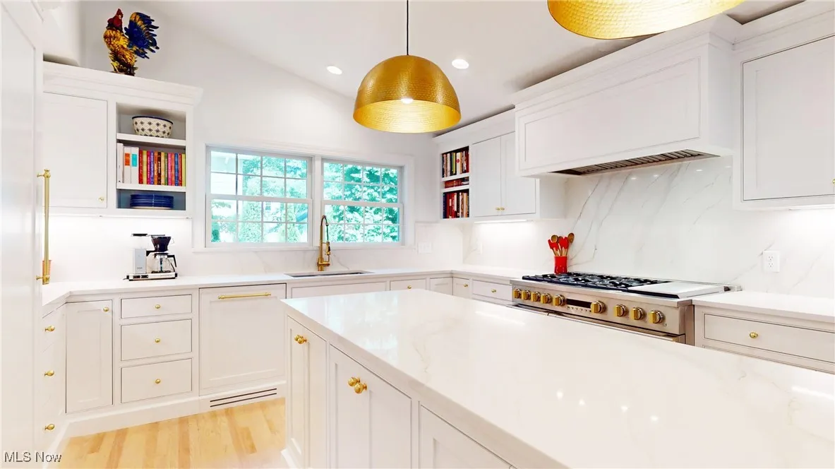 Kitchen featuring open shelves, GE Mongram range with gas cooktop, white cabinetry, quartz countertops and fulll backsplash