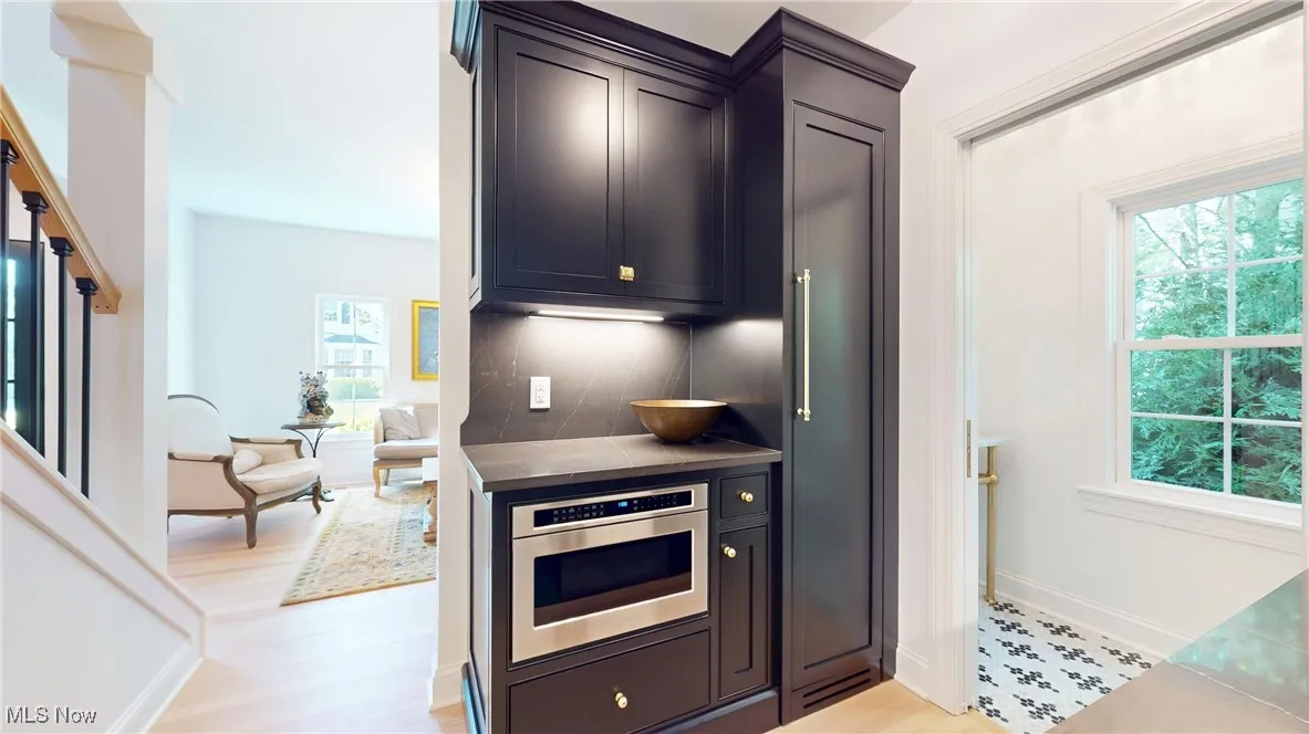 Butler pantry featuring plenty of natural light, stainless steel microwave, and large paneled freezer