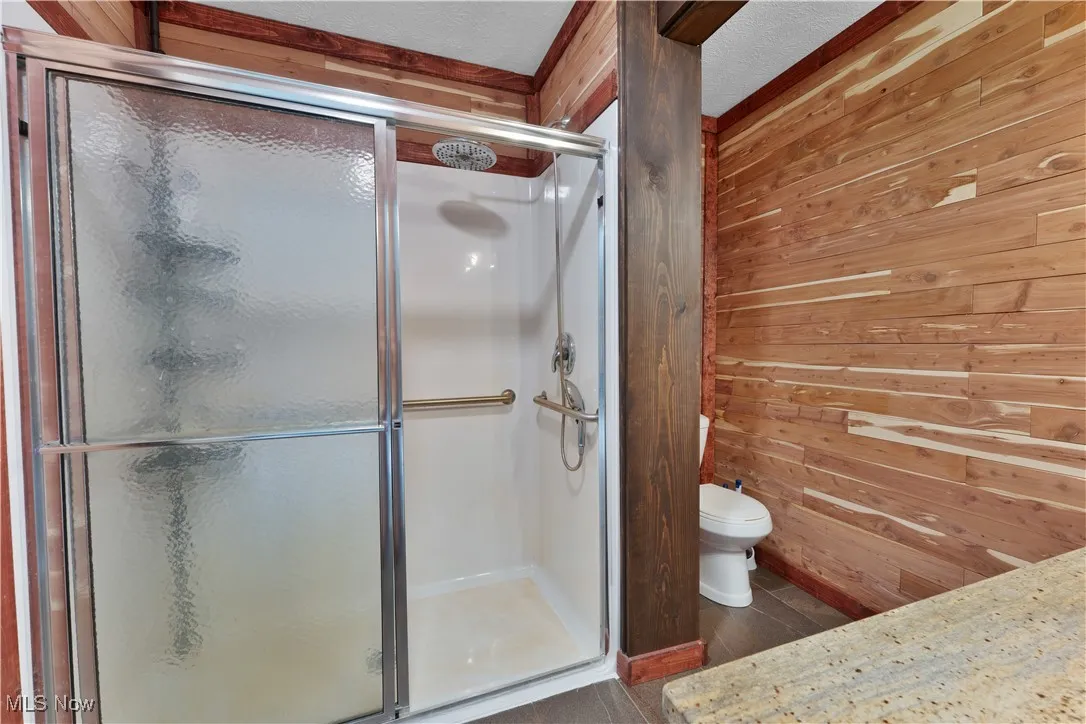Bathroom with wood walls, a shower stall, and vanity