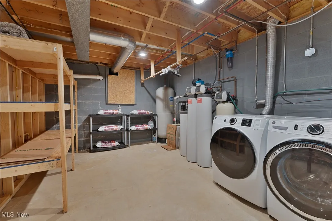 Washroom featuring separate washer and dryer and concrete block wall