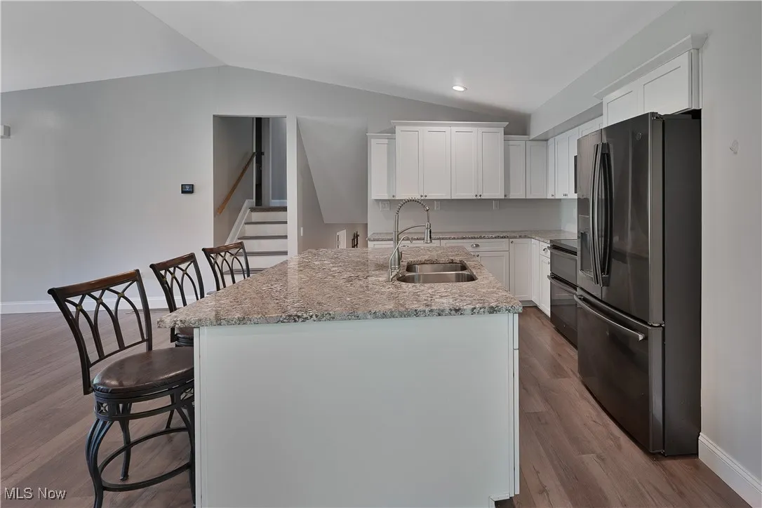 Kitchen with refrigerator with ice dispenser, lofted ceiling, white cabinets, dark wood-style floors, and recessed lighting