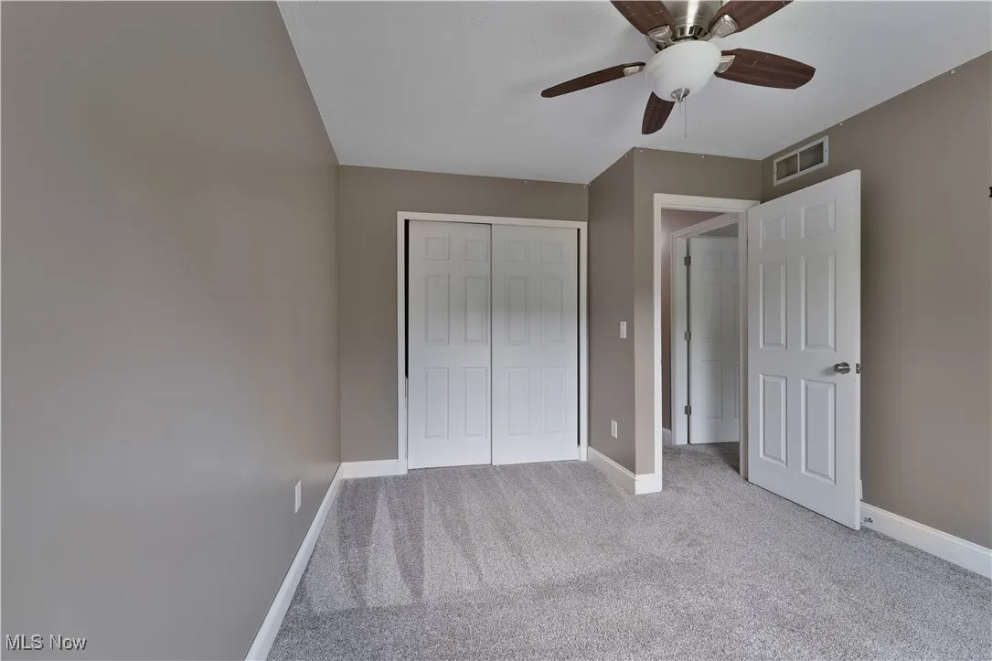 Unfurnished bedroom with light colored carpet, a closet, and a ceiling fan