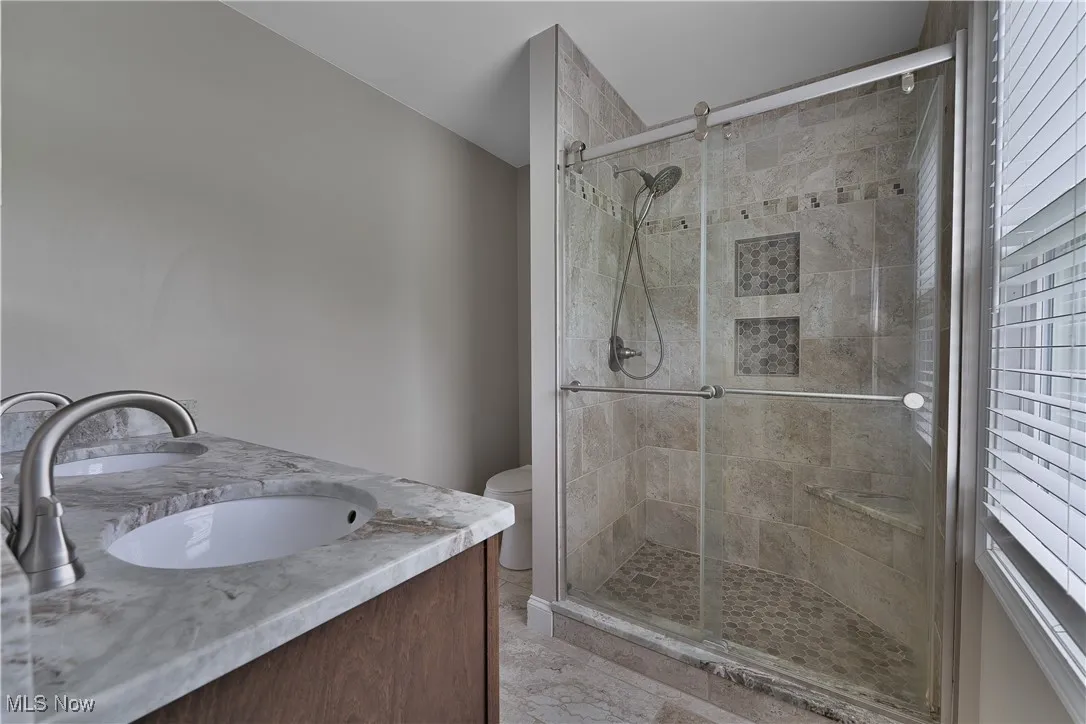 Full bath with double vanity and a stall shower