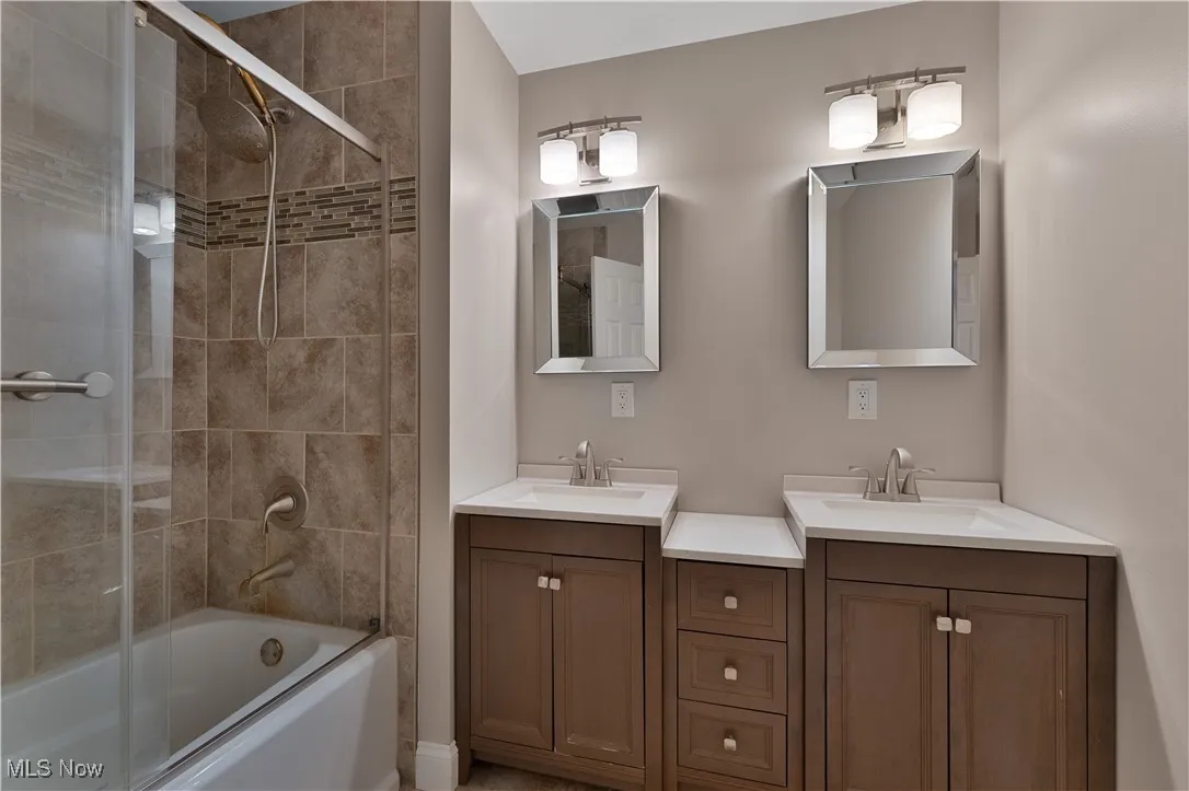 Full bathroom featuring double vanity and enclosed tub / shower combo
