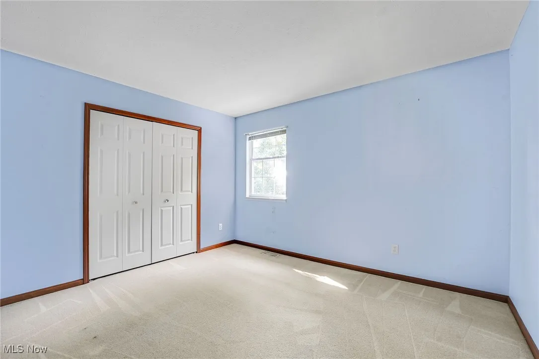 Unfurnished bedroom with light colored carpet and a closet