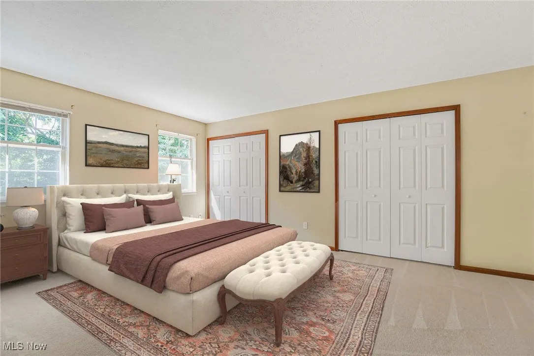 Virtually stage Bedroom featuring multiple closets, light colored carpet, and multiple windows