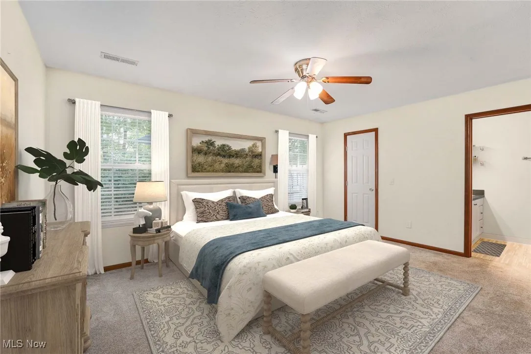 Virtually stage Bedroom featuring light carpet, multiple windows, a ceiling fan, and ensuite bath