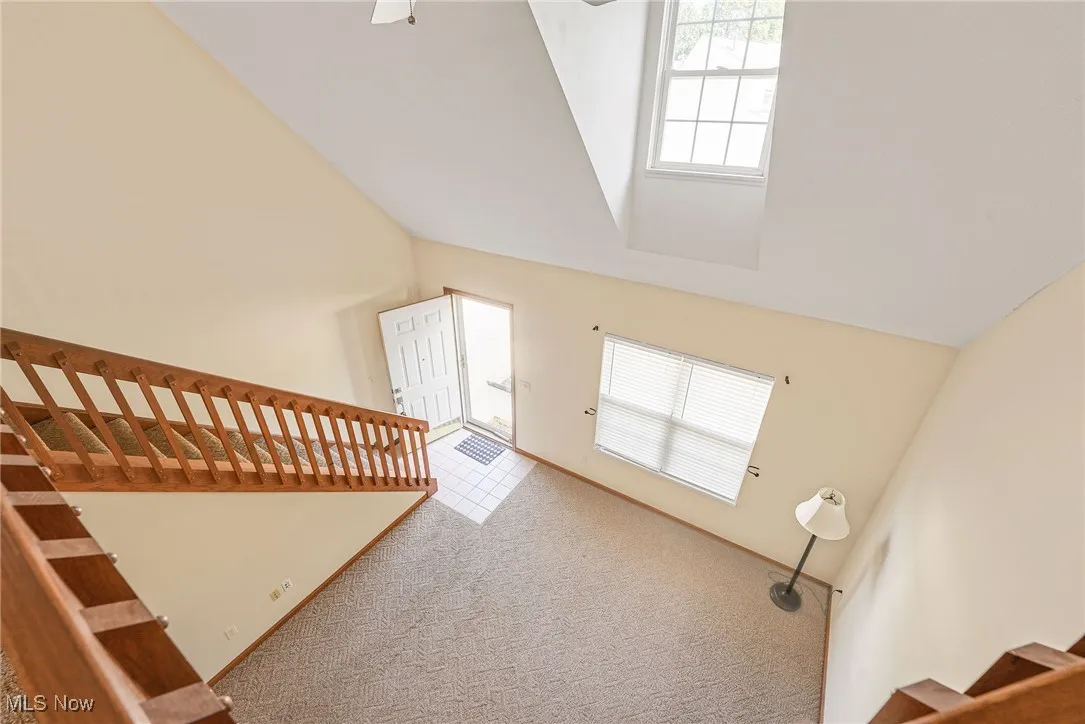 Stairway with carpet flooring and high vaulted ceiling