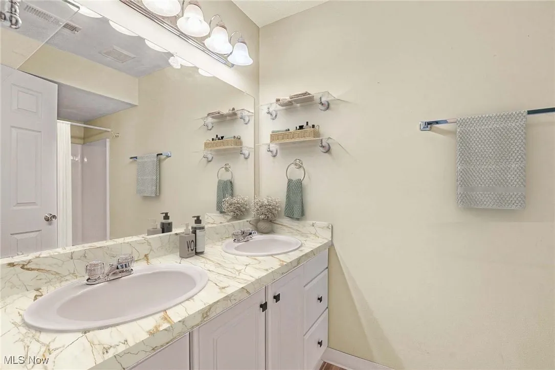 Virtually stage Bathroom featuring double vanity and a shower