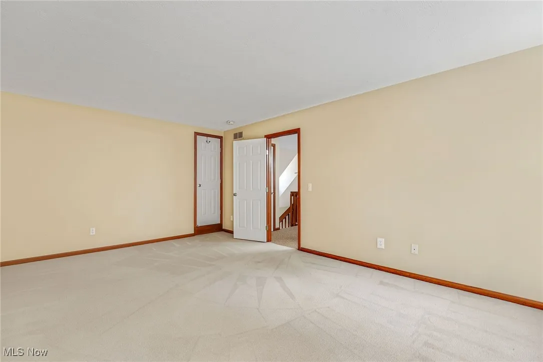 Unfurnished room featuring light carpet and baseboards