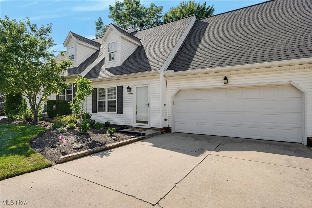 View of front facade featuring driveway, a shingled roof, and a garage