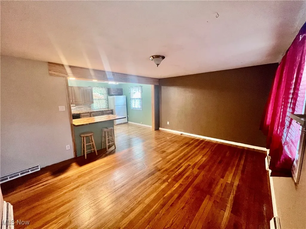 Unfurnished living room with light wood finished floors and a baseboard heating unit