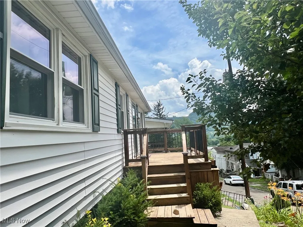 View of property exterior featuring a deck and stairway