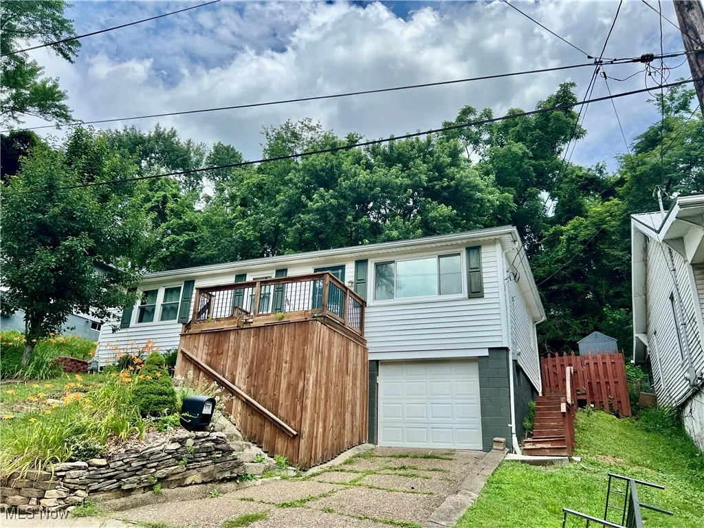 View of front facade featuring an attached garage, stairway, and driveway