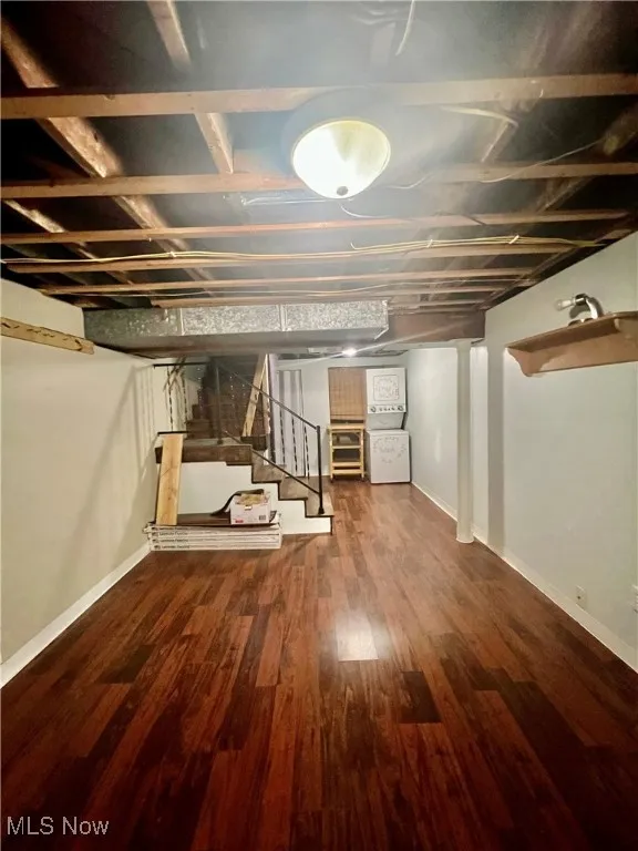 Finished below grade area with stairs, washer / dryer, and dark wood-style floors