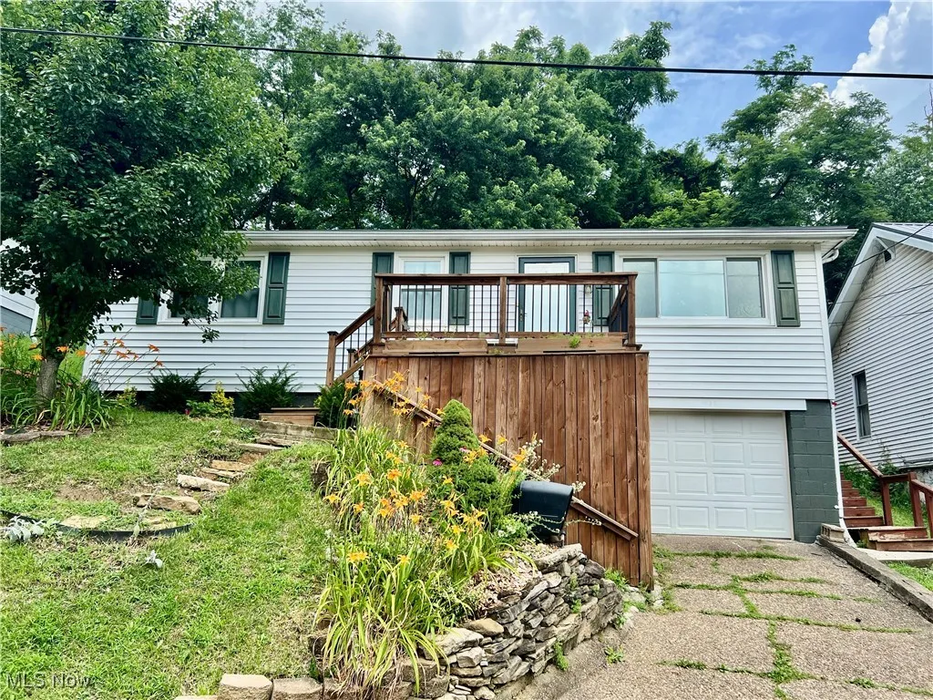 Ranch-style home featuring an attached garage, driveway, and a wooden deck
