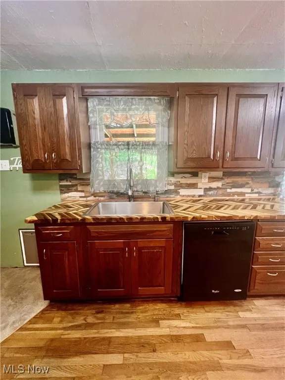 Kitchen featuring dishwasher, backsplash, and light wood-style floors