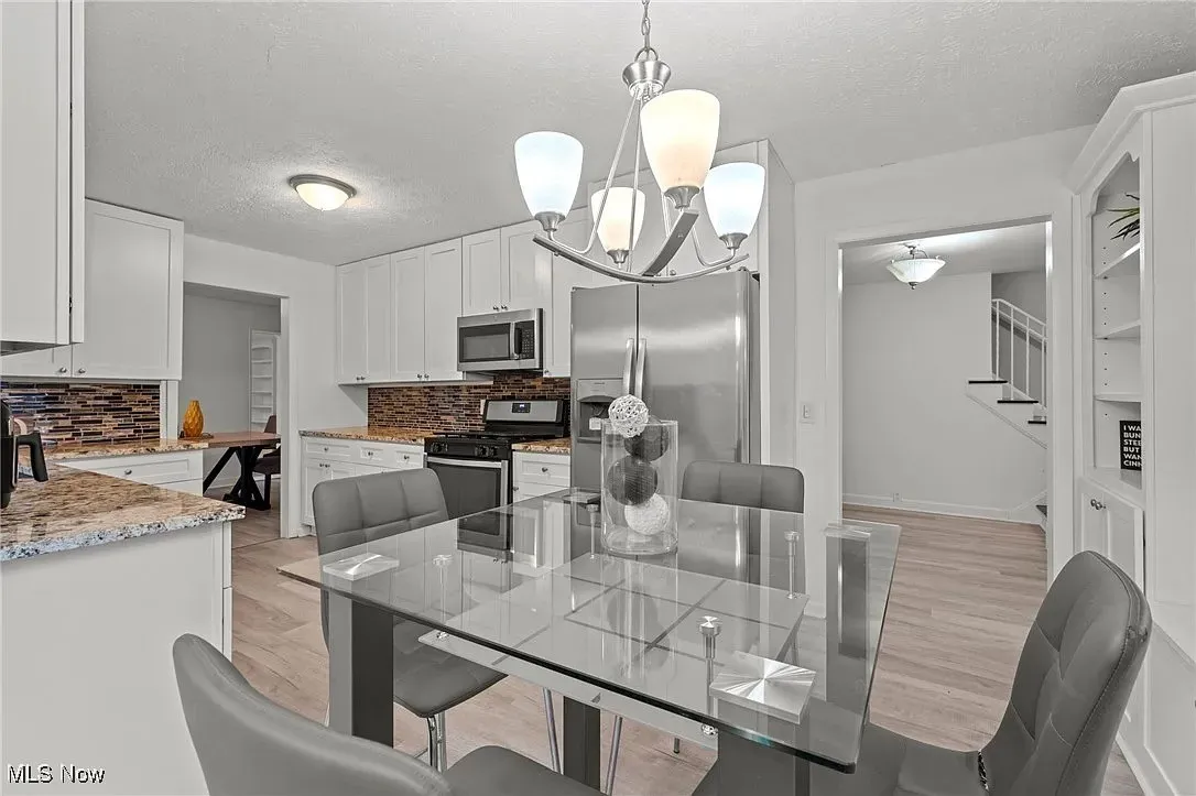 Dining area featuring a chandelier, light wood-style floors, a textured ceiling, and stairs