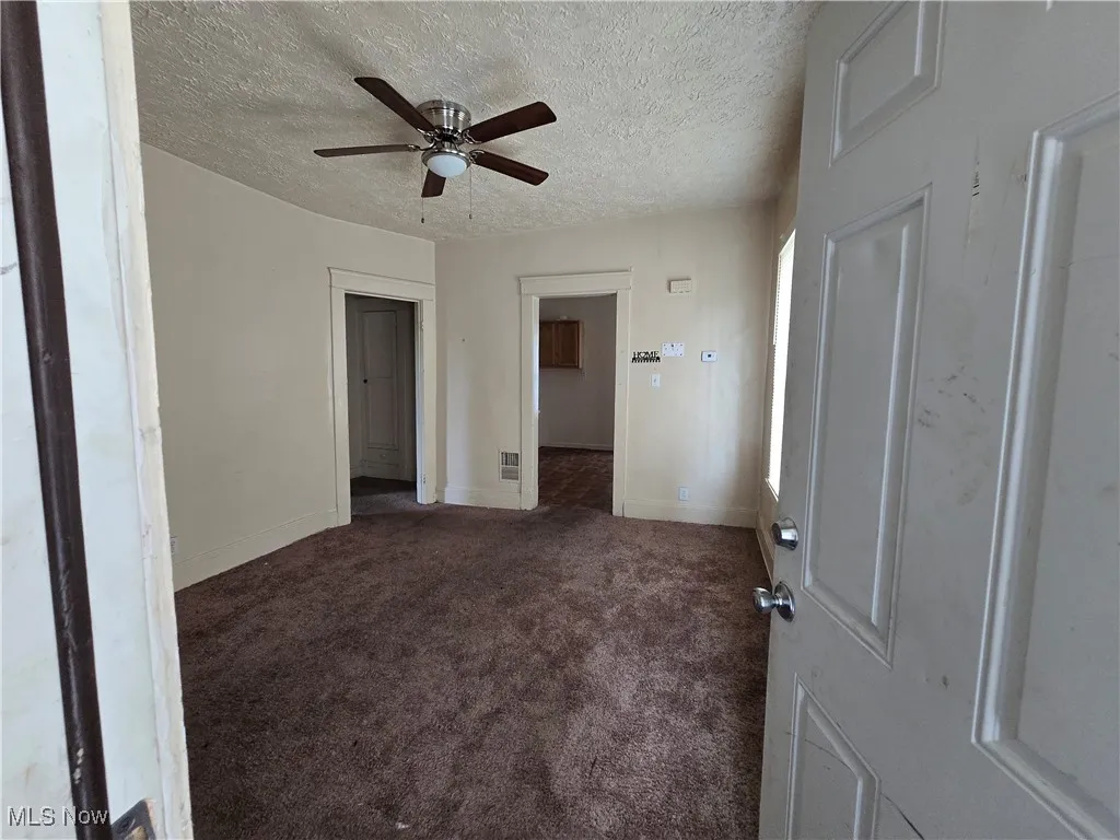 Spare room featuring ceiling fan, carpet, and a textured ceiling