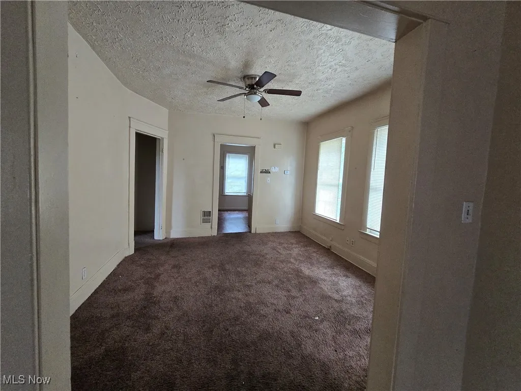 Spare room with ceiling fan, a textured ceiling, and carpet