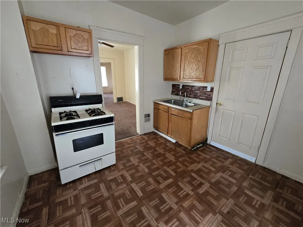 Kitchen with white range with gas cooktop, light countertops, and backsplash