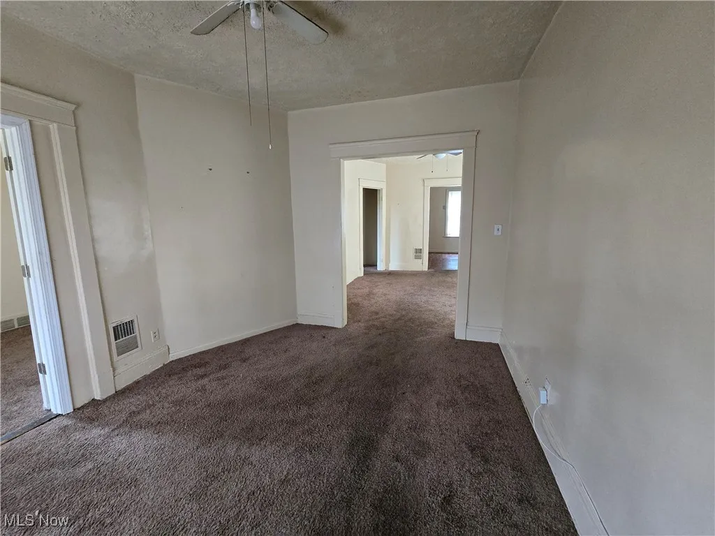 Spare room featuring a ceiling fan, carpet flooring, and a textured ceiling