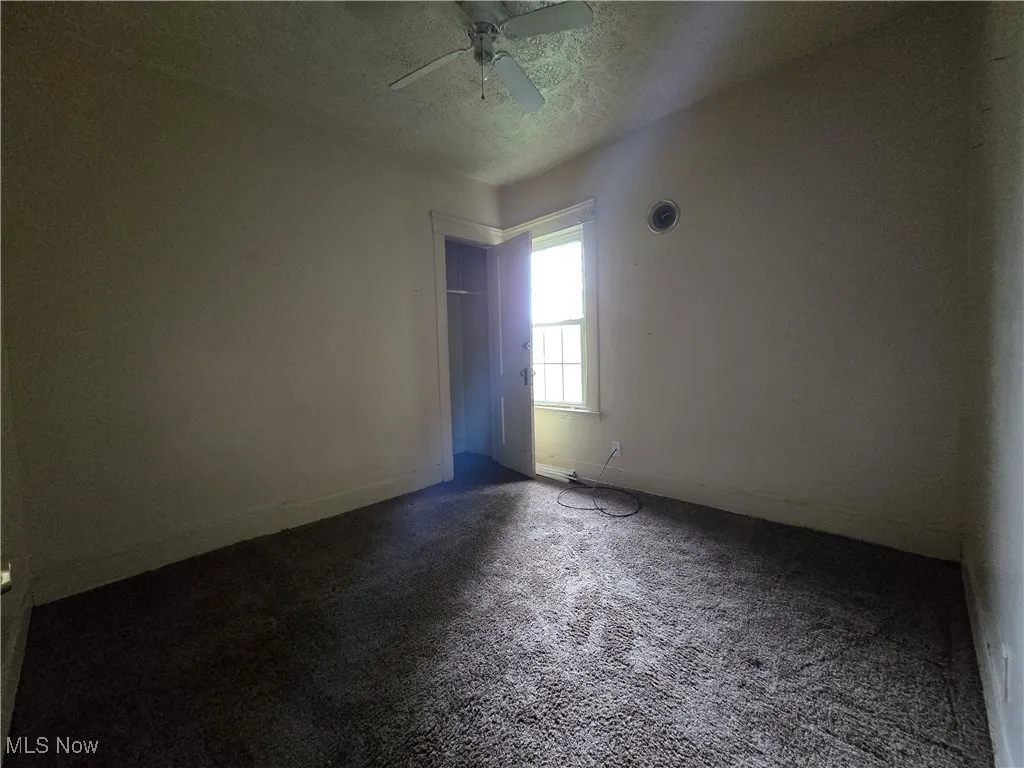 Unfurnished room with a ceiling fan, carpet floors, and a textured ceiling