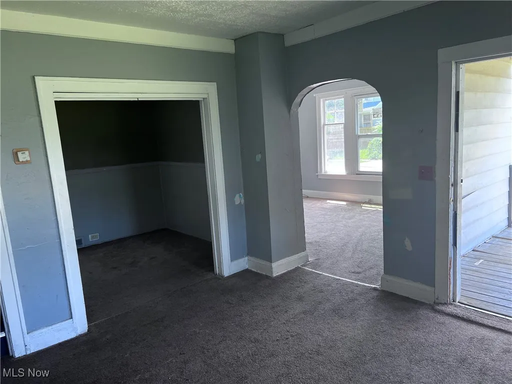 Spare room featuring arched walkways, carpet, and a textured ceiling