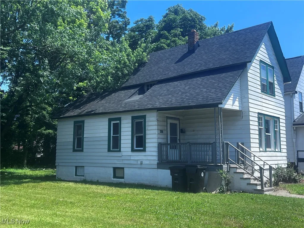 View of front of home featuring a chimney, a front yard, roof with shingles, and a porch