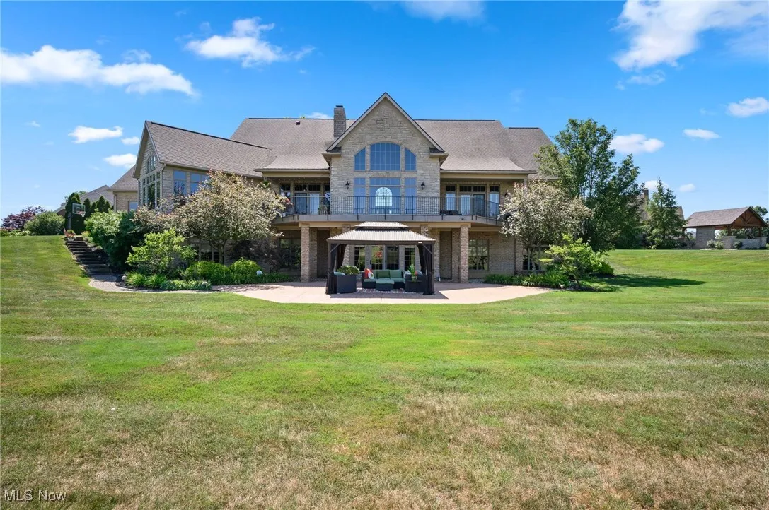 Rear view of property with a balcony, a gazebo, a patio area, an outdoor living space, and a yard