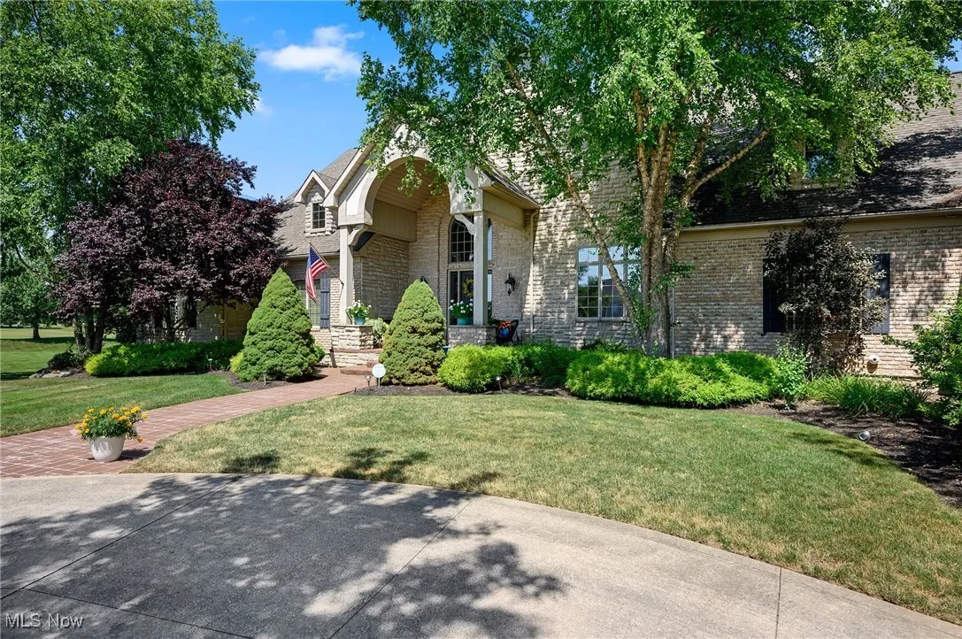 View of front of property with a front yard, brick siding, and stone siding