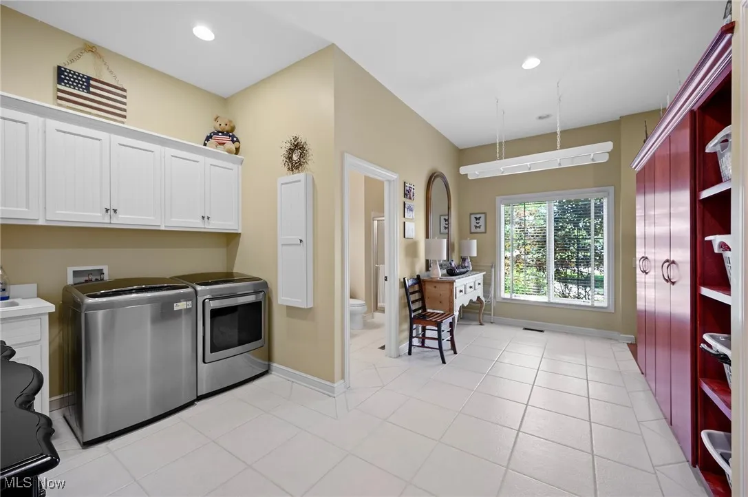 Laundry room featuring washing machine and dryer, cabinet space, light tile patterned flooring, and recessed lighting