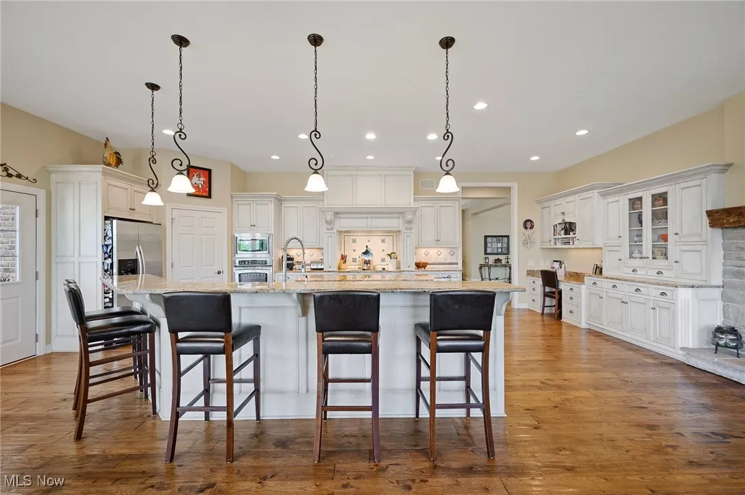 Kitchen featuring appliances with stainless steel finishes, recessed lighting, white cabinets, a spacious island, and a breakfast bar area