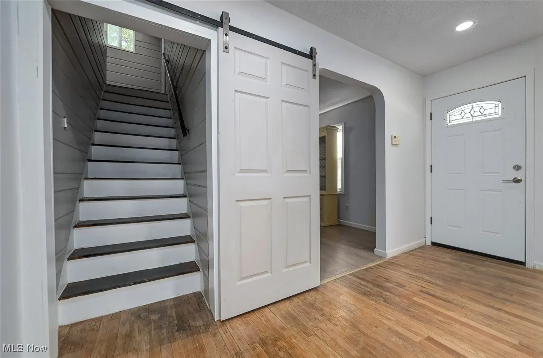 Entryway featuring light wood-type flooring, recessed lighting, stairway, arched walkways, and a barn door