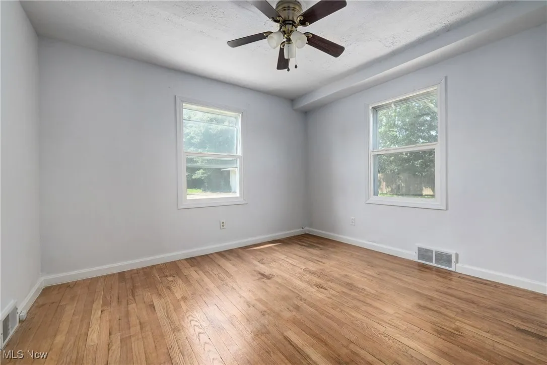 Spare room with healthy amount of natural light, light wood-type flooring, and ceiling fan