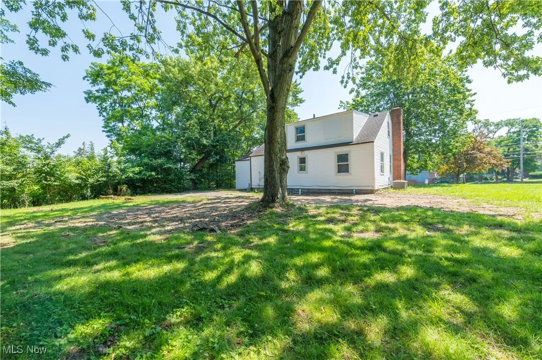Back of property with a chimney and a yard