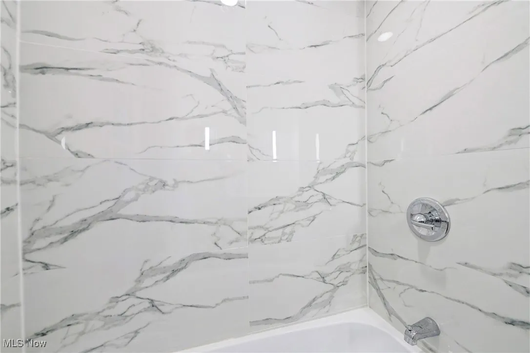 Bathroom featuring a combined bath / shower with marble appearance