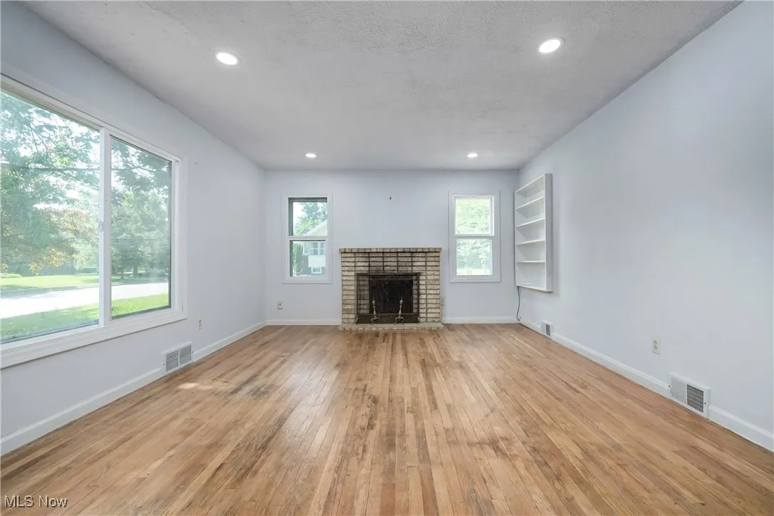 Unfurnished living room featuring light wood finished floors, a fireplace, and recessed lighting