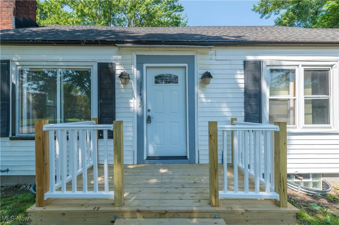 Entrance to property featuring a wooden deck and roof with shingles