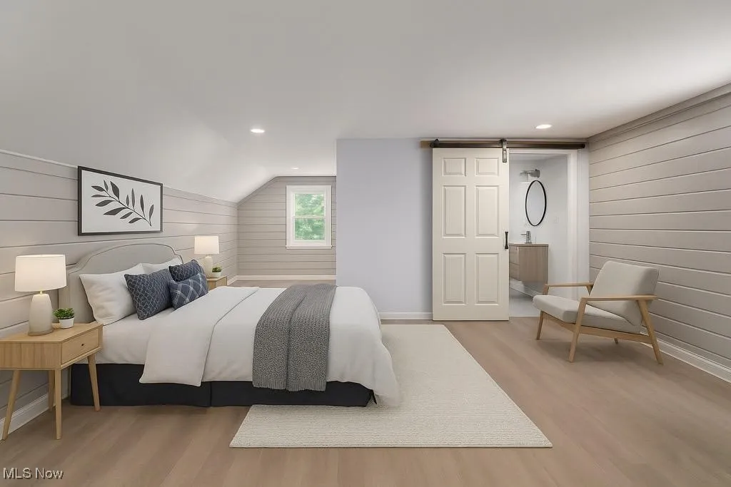 VIRTUALLY STAGED PHOTO!!Bedroom with a barn door, wooden walls, light wood finished floors, recessed lighting, and lofted ceiling