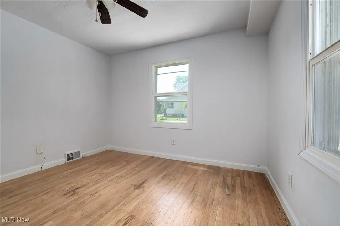 Empty room with light wood finished floors and a ceiling fan