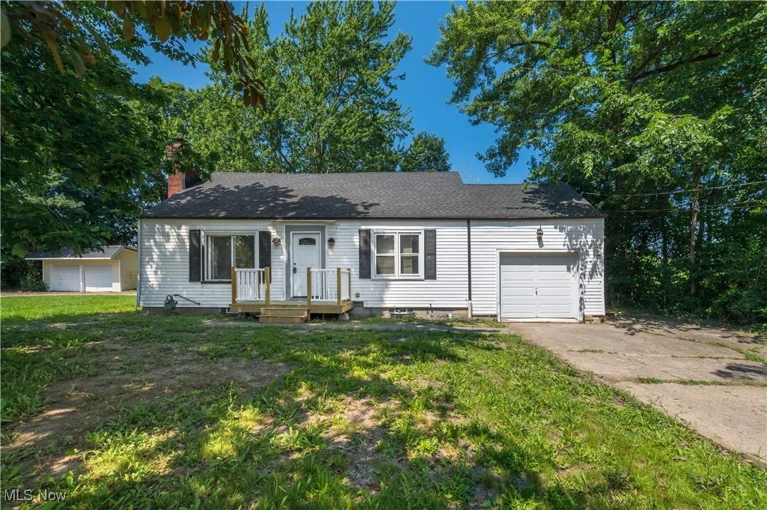 Ranch-style house with concrete driveway, an attached garage, a chimney, and a front lawn