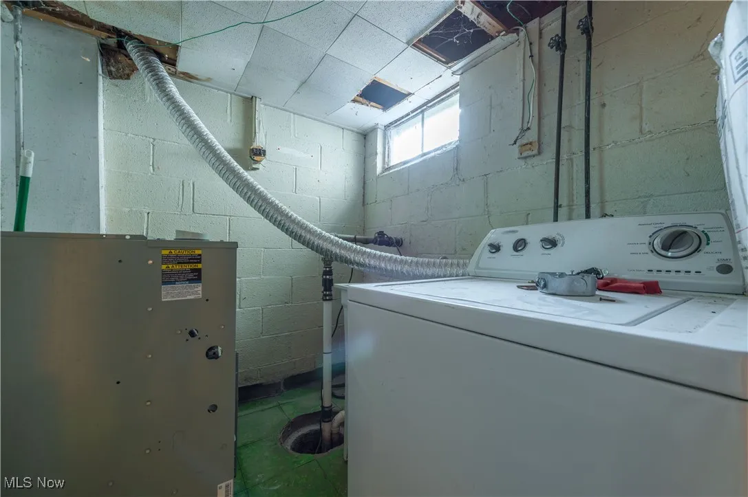 Laundry area featuring washer / clothes dryer and concrete block wall