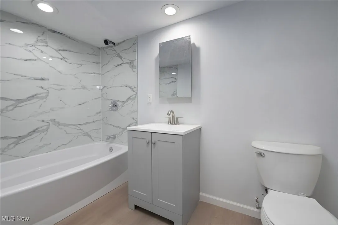 Full bath featuring vanity, shower / bathtub combination, wood finished floors, and recessed lighting