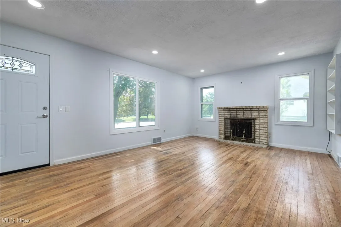 Unfurnished living room with hardwood / wood-style flooring, recessed lighting, a fireplace, and a textured ceiling